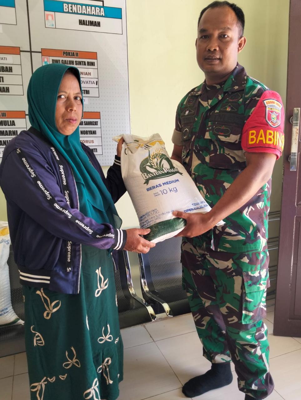 Bersama Aparat Desa Pemuda Sertu Triyono Bantu Salurkan Bantuan Pangan Beras Kepada Masyarakat Penerima Manfaat